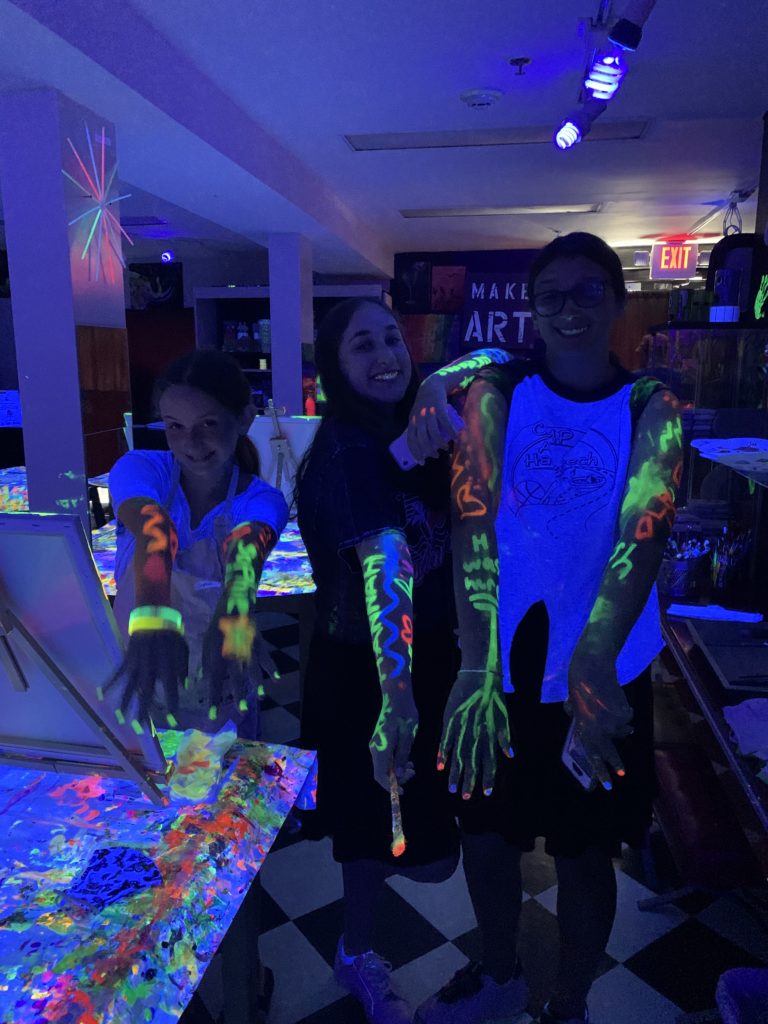 three people with glow-in-the-dark paint on their arms