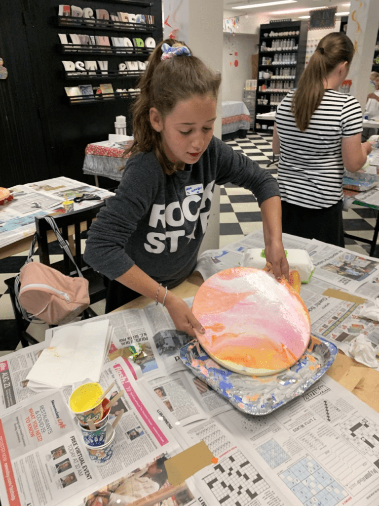 A vibrant piece of artwork created by a child using the paint pouring technique